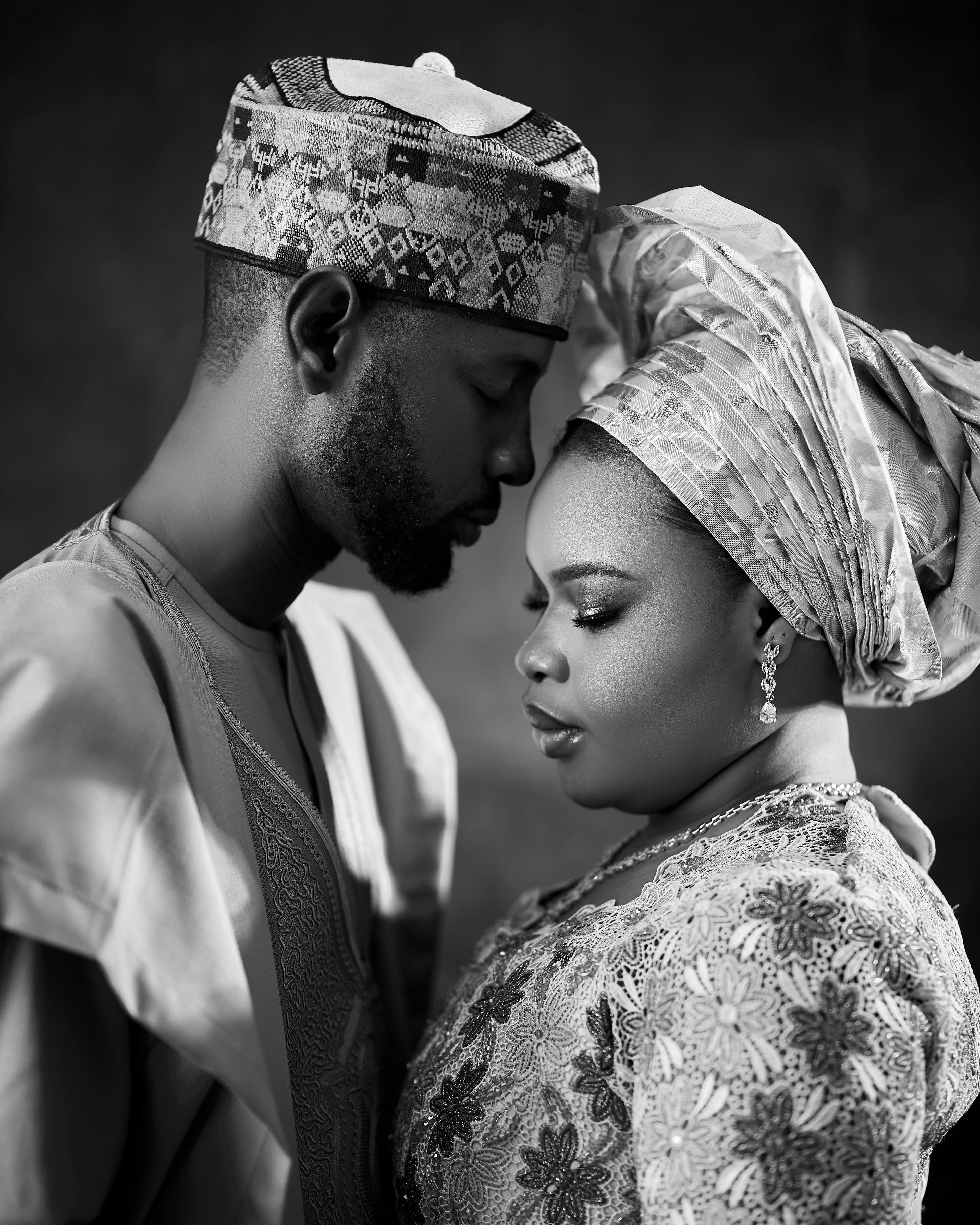 Black-and-white portrait of a couple in traditional attire, foreheads touching, eyes closed